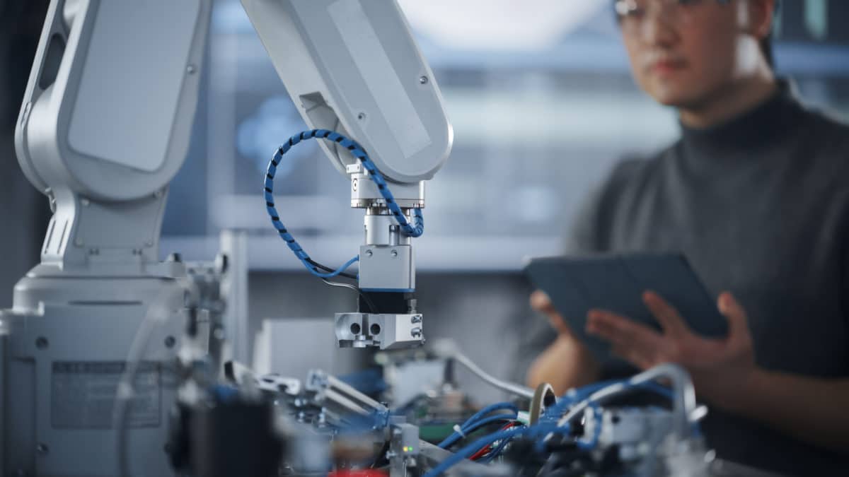Custom Solutions. Engineer Holding a Custom Solutions Tablet and Controlling a moving Robot