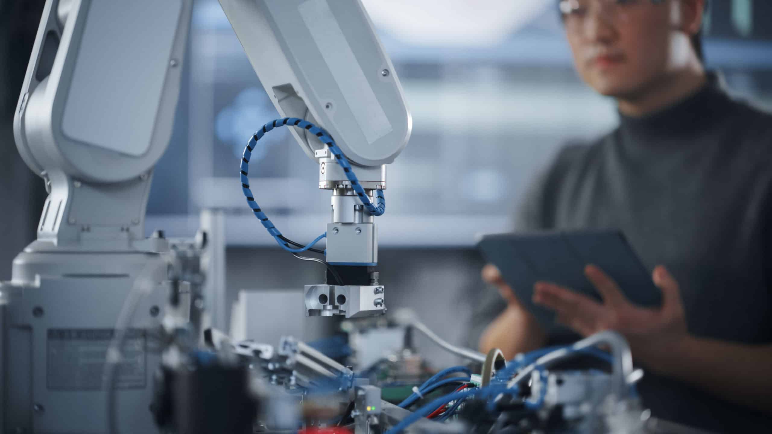 Custom Solutions. Engineer Holding a Custom Solutions Tablet and Controlling a moving Robot