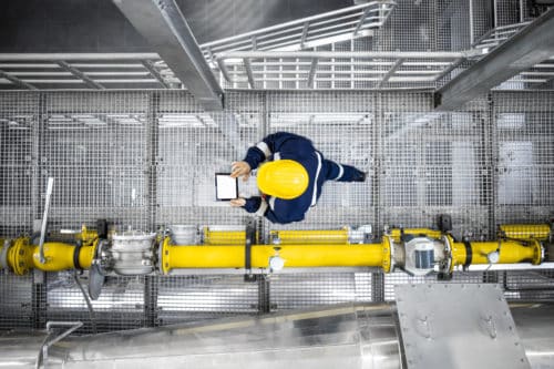 Top view of oil & gas worker walking by gas pipes, checking metering soluiton