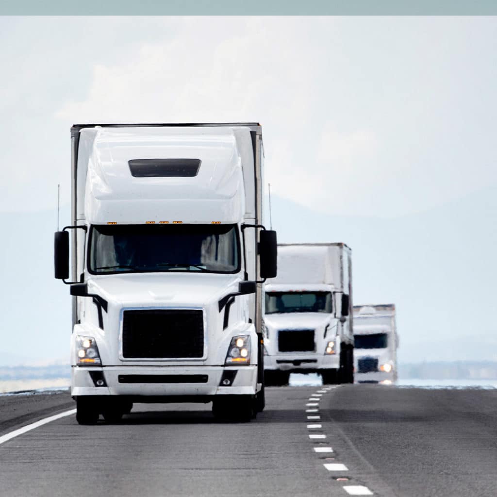 Three similar white trucks on the road