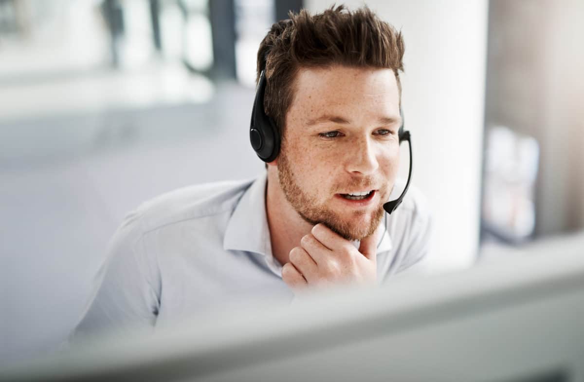 Shot of a young man sitting in front of a computer, wearing a headset